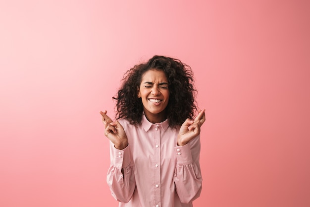 Imagen de mujer africana joven emocional posando aislada vestida con pijama hacer gesto de esperanza.