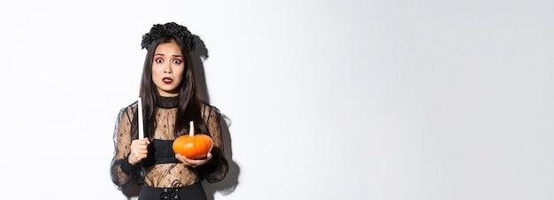 Imagen de una mujer asiática entrando en pánico teniendo miedo de la brujería en halloween de pie con un disfraz de bruja