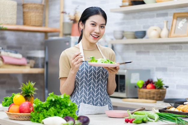 Imagen de mujer asiática preparando ensalada en la cocina