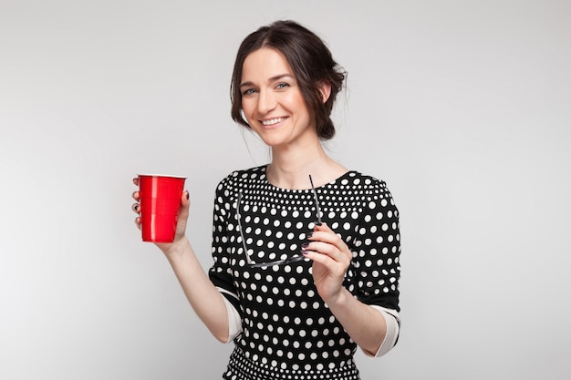 Imagen de una mujer atractiva en ropa manchada de pie con una taza en las manos