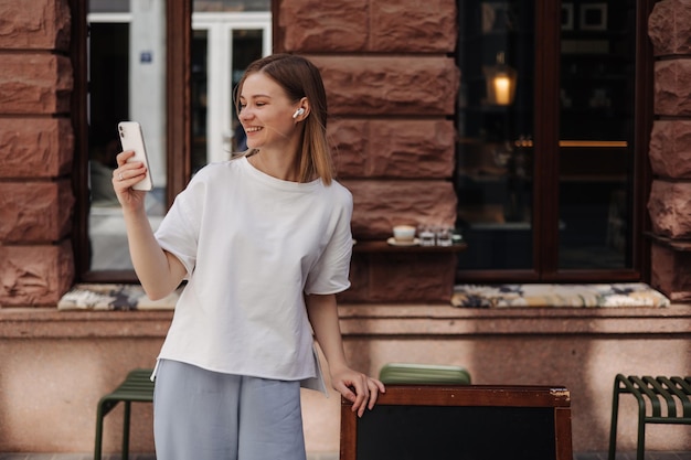 Imagen de una mujer atractiva sonriendo a un smartphone en la calle