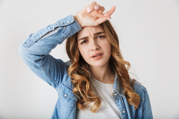 Imagen de una mujer bonita joven cansada hermosa que presenta aislada sobre la pared blanca.