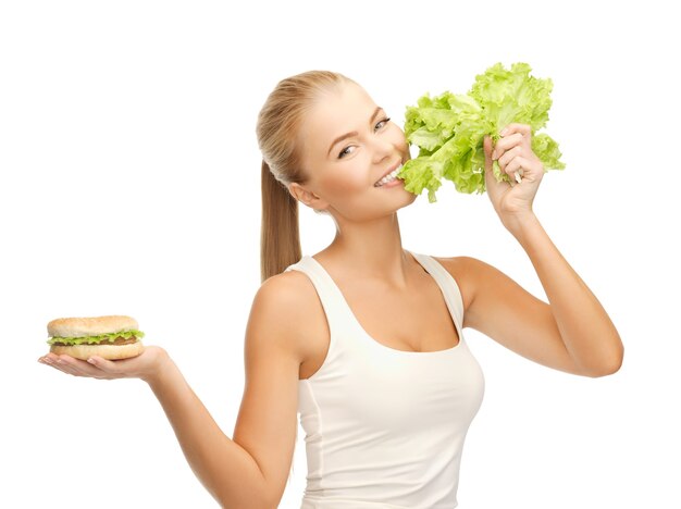 Imagen de mujer deportiva con lechuga verde y hamburguesa