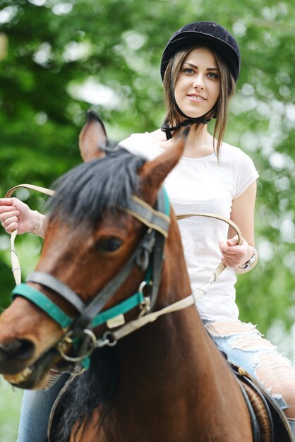 Imagen de mujer feliz sentado a caballo en la granja del pueblo