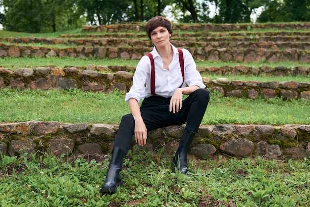 Imagen de una mujer hermosa y elegante con una camisa blanca, pantalones negros y tirantes rojos El concepto de estilo y moda