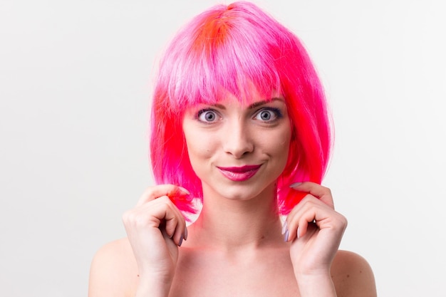 Imagen de una mujer hermosa y emocionada con peluca riéndose mientras posa con dulces aislados sobre un fondo rosa