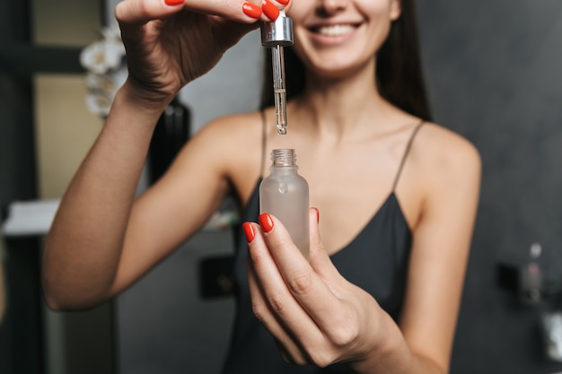 Imagen de mujer hermosa joven en el baño cuida su piel con cosméticos.