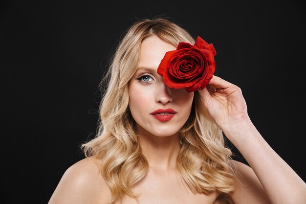 Imagen de mujer hermosa joven con labios rojos maquillaje brillante posando aislado con flor rosa.