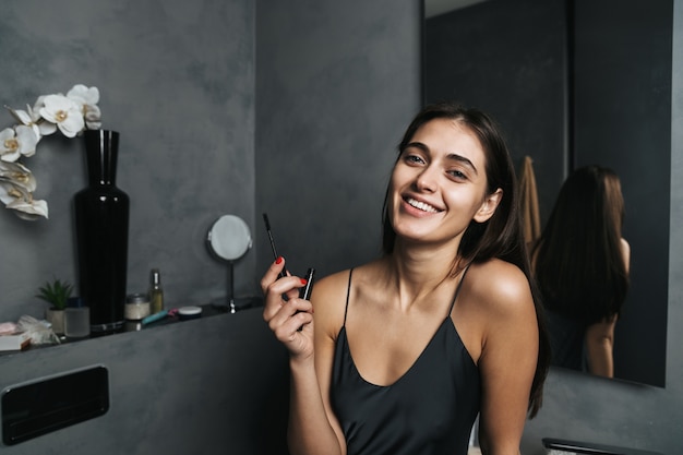 Imagen de una mujer hermosa joven linda alegre en el baño cuida su piel haciendo maquillaje.