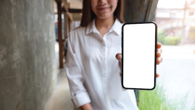 Imagen de una mujer hermosa que muestra un teléfono móvil con una pantalla en blanco