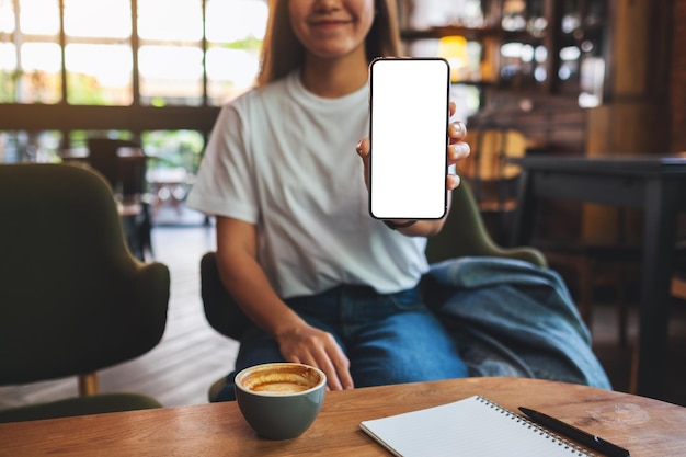 Imagen de una mujer hermosa que muestra un teléfono móvil con una pantalla en blanco