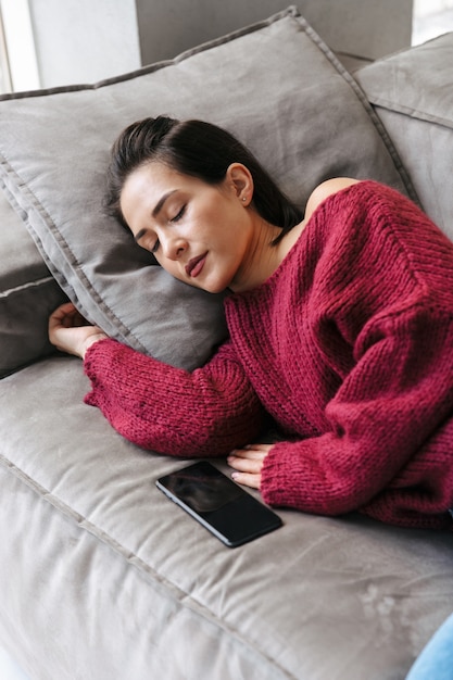 Imagen de una mujer en el interior de su casa en el sofá durmiendo tiene un descanso se encuentra.