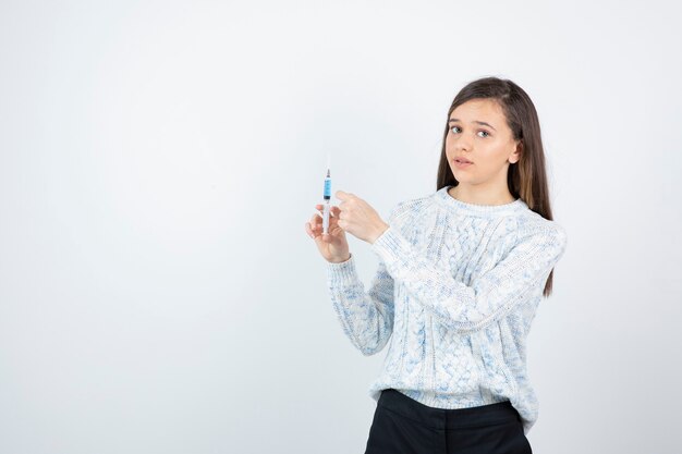 Imagen de mujer joven bonita con pie de jeringa médica.