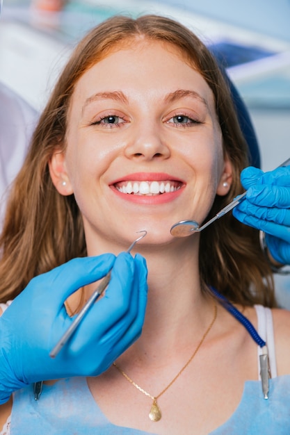 Imagen de una mujer joven y bonita sentada en un sillón dental en el centro médico mientras un profesional médico repara los dientes.