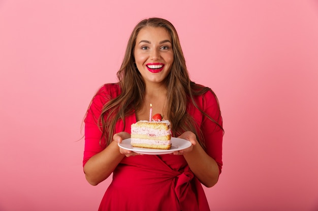 Foto imagen de una mujer joven hambrienta emocionada aislada sobre pared rosa con pastel.