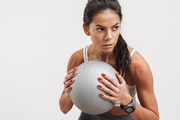 Foto imagen de mujer joven morena en ropa deportiva sosteniendo la pelota de fitness durante el entrenamiento