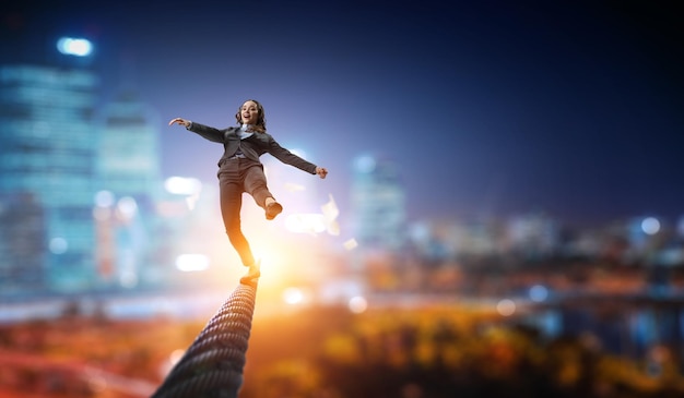 Imagen de una mujer de negocios balanceándose en una cuerda. concepto de riesgo. Técnica mixta