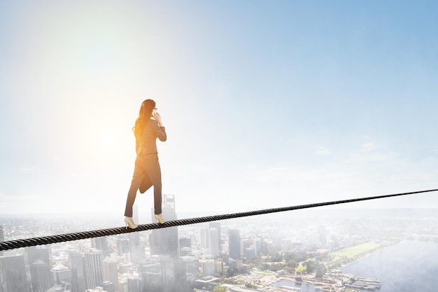 Imagen de una mujer de negocios balanceándose en una cuerda. concepto de riesgo. Técnica mixta