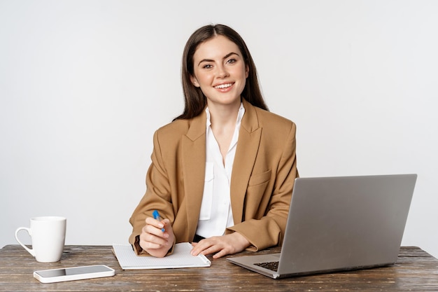 Imagen de una mujer de negocios que trabaja en la oficina sentada a la mesa con una computadora portátil escribiendo documentos posando para...