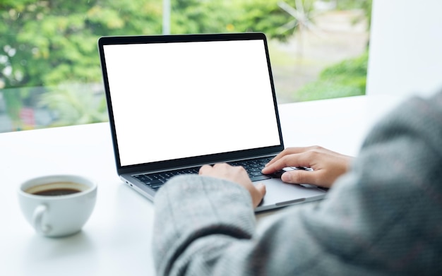 Imagen de una mujer de negocios que usa y escribe en el teclado de una computadora portátil con una pantalla de escritorio en blanco en la oficina