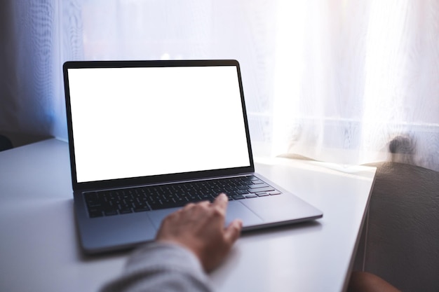 Imagen de una mujer de negocios que usa y toca el panel táctil de una computadora portátil con una pantalla de escritorio en blanco en la mesa