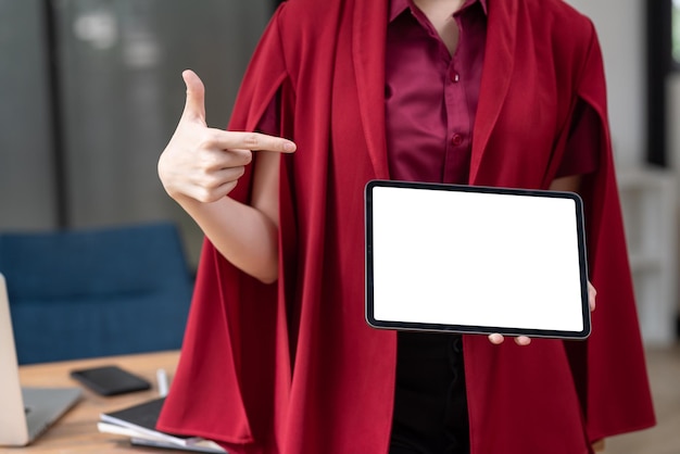 Imagen de mujer de negocios con un vestido rojo sosteniendo un apuntando a una pantalla blanca en blanco de tableta en la oficina. Bosquejo.