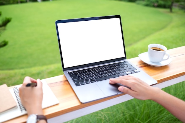 Imagen de una mujer que usa una computadora portátil con una pantalla de escritorio blanca en blanco mientras trabaja al aire libre