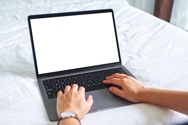 Imagen de una mujer que usa y escribe en una computadora portátil con un teclado de pantalla de escritorio en blanco en la cama