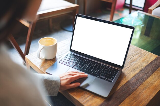 Imagen de una mujer que usa y toca el panel táctil de una computadora portátil con una pantalla de escritorio blanca en blanco en un café