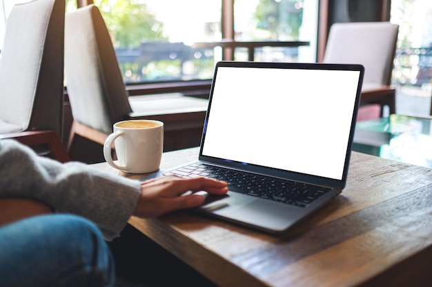 Imagen de una mujer que usa y toca el panel táctil de una computadora portátil con una pantalla de escritorio blanca en blanco en un café