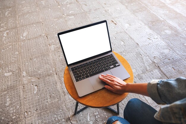 Imagen de una mujer que usa y toca el panel táctil de una computadora portátil con una pantalla de escritorio en blanco en la mesa