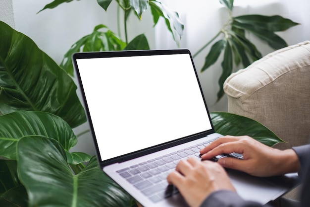 Foto imagen de una mujer que usa y trabaja en una computadora portátil con una pantalla de escritorio blanca en blanco en casa