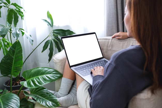 Imagen de una mujer que usa y trabaja en una computadora portátil con una pantalla de escritorio blanca en blanco en casa