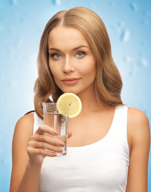 imagen de mujer con rodaja de limón en un vaso de agua.