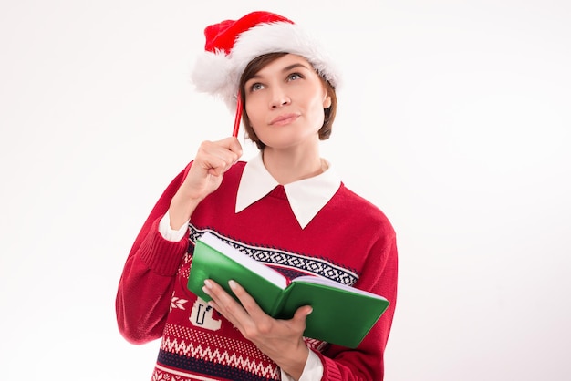 Imagen de una mujer en ropa de Navidad sobre un fondo blanco. Hacer una lista de deseos. Concepto de vacaciones. Técnica mixta