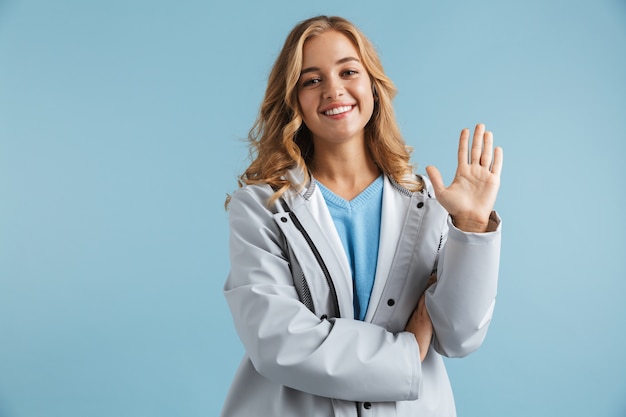 Imagen de mujer rubia caucásica de 20 años vistiendo impermeable sonriendo