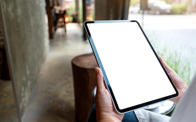 Imagen de una mujer sosteniendo una tableta digital con una pantalla de escritorio en blanco en un café