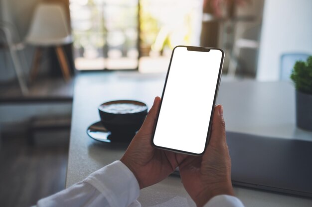 Imagen de una mujer sosteniendo un teléfono móvil con una pantalla de escritorio blanca en blanco en la oficina