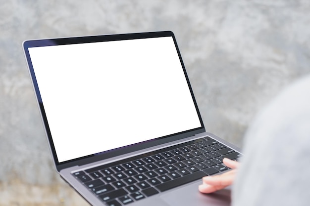 Imagen de una mujer sosteniendo y usando una computadora portátil con una pantalla de escritorio blanca en blanco al aire libre