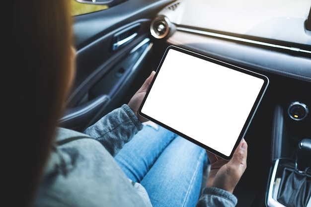 Imagen de una mujer sosteniendo y usando una tableta digital con pantalla en blanco en el auto