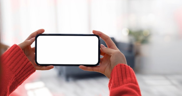 Imagen de una mujer sosteniendo y usando un teléfono móvil con una pantalla de escritorio en blanco en vista horizontal