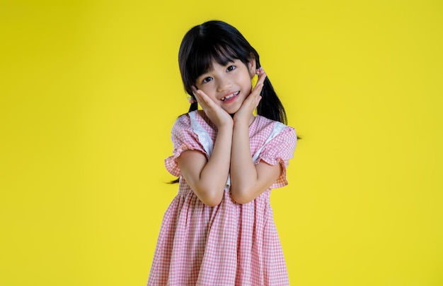 Imagen de una niña asiática posando sobre un fondo amarillo