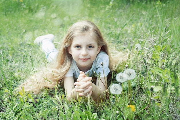 Imagen de una niña bonita acostada en el campo de dientes de león