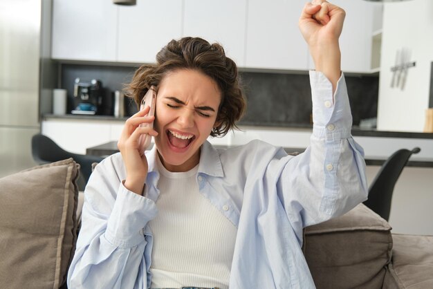 Imagen de una niña celebrando sosteniendo un teléfono inteligente y animando por la emoción de ganar, recibe una gran noticia