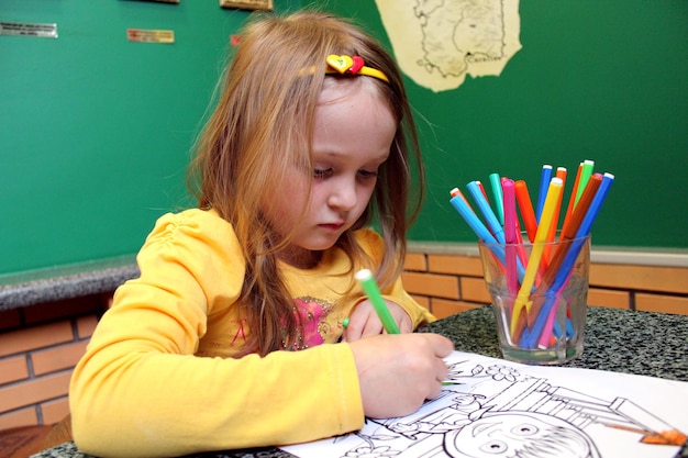 Imagen de una niña dibujando en la mesa.