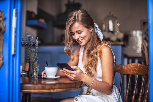 Imagen de niña feliz bastante emocional sentado en la cafetería hablando por teléfono móvil.