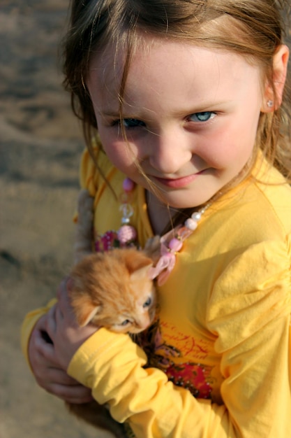 Imagen de una niña con un gatito rojo