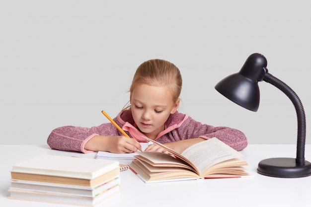 Imagen de niña seria concentrada escribe registros en cuaderno