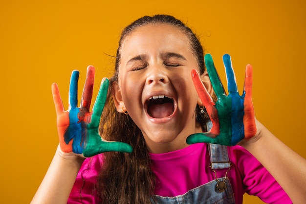 Una imagen de una niña con sus manos en pintura.