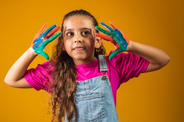 Una imagen de una niña con sus manos en pintura.